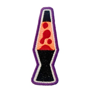 May include: A purple and white embroidered patch of a lava lamp with a black base and orange and red lava.