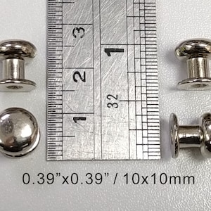以下が含まれることがあります： 丸い頭とポストが付いた銀色の金属製押しボタンのスナップが4つ。スナップは直径0.39インチで、サイズ比較のために定規の隣に置かれています。 0.39" x 0.39" / 10x10mm
