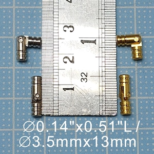 May include: Four metal cabinet hinges, two silver and two gold, are shown next to a ruler. The ruler measures 1 inch and 32nds of an inch. The hinges are 0.14 inches by 0.51 inches, or 3.5 mm by 13 mm.