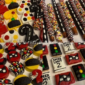 May include: A collection of race car themed treats for a birthday party. The treats include chocolate-covered pretzels, chocolate-covered Oreos, Rice Krispie treats, and cake pops. The treats are decorated with red, black, white, and yellow icing and sprinkles. The treats are arranged on a white surface. The text "Speed Limit 2" is visible on some of the treats.