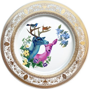 Puede incluir: Un plato de cerámica blanco con un borde dorado y un diseño floral con dos ciervos, un pájaro azul y un pájaro rojo. El plato tiene un borde dorado y un diseño floral.