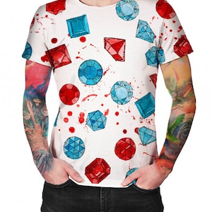 Può includere: Maglietta bianca con un motivo di pietre preziose rosse e blu. Le pietre preziose sono sparse casualmente sulla maglietta e sembrano essere dipinte.