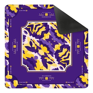 May include: A square game mat featuring a purple and yellow abstract camouflage pattern. The center is framed by a solid purple border with white text reading THE CHARLESTON, PLAY RIGHT, and WALLS LEFT. The underside of the mat is solid black.