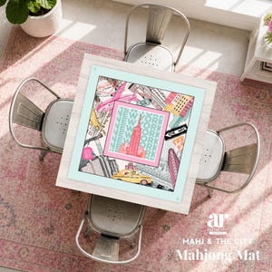 May include: A square mahjong mat with a New York City theme, featuring iconic landmarks like the Empire State Building and a yellow taxi. The mat is framed in light blue and surrounded by four metal chairs and a pink rug. The text "NEW YORK" is repeated on the mat.