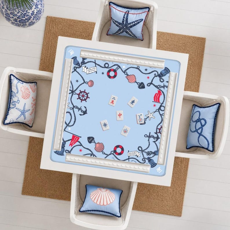 May include: A square white games table with a light blue surface featuring a nautical pattern of ropes, anchors, life rings, and seashells. Six mahjong tiles are placed in the centre. Four chairs with light blue nautical-themed cushions surround it.