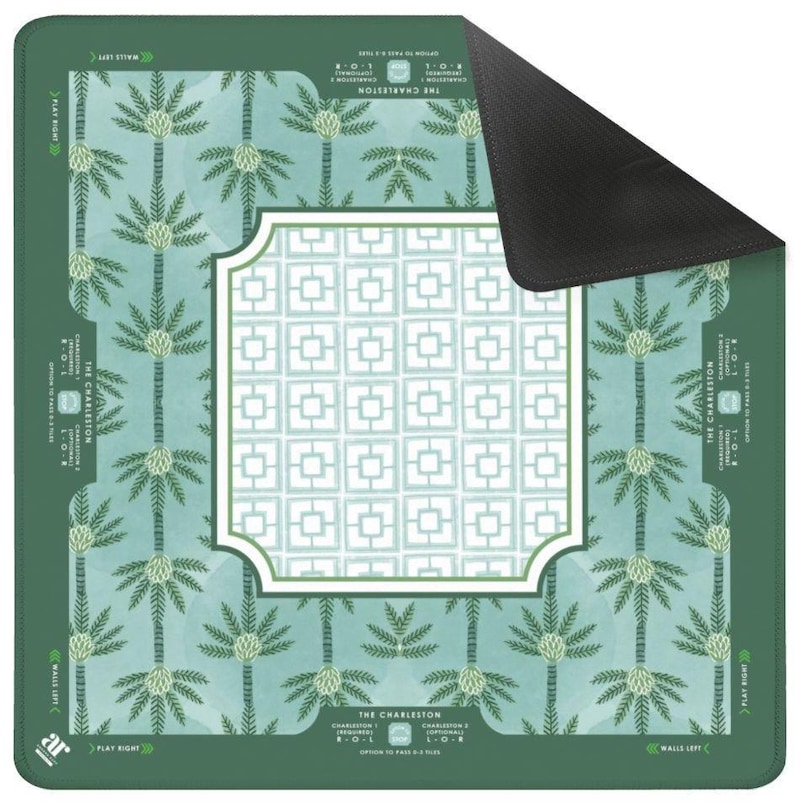 May include: A rectangular game mat in shades of green and teal, featuring a palm tree design and a white geometric pattern. The mat includes the text "THE CHARLESTON" and game instructions. The reverse side of the mat is black.