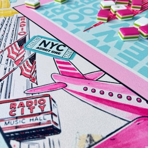 May include: A board game with a New York City theme. The game board features a pink airplane, the Radio City Music Hall, and an NYC admit one ticket. Pink, white, and green game pieces are scattered across a light blue and pink game board.