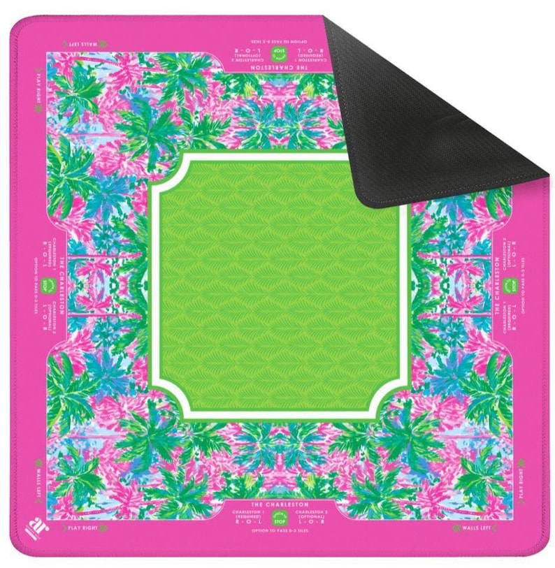 Pode incluir: Um tapete retangular rosa com um design central verde e branco. O tapete apresenta um padr&atilde;o floral em rosa, azul e verde. O texto "THE CHARLESTON" &eacute; vis&iacute;vel no tapete.