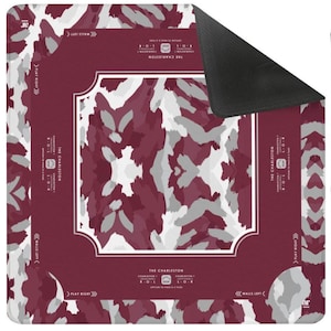 May include: A square game mat featuring a maroon, white, and gray abstract camouflage pattern. The center has a white-bordered frame, and the edges include text reading THE CHARLESTON, CHARLESTON 1, PLAY RIGHT, and WALLS LEFT with directional arrows.