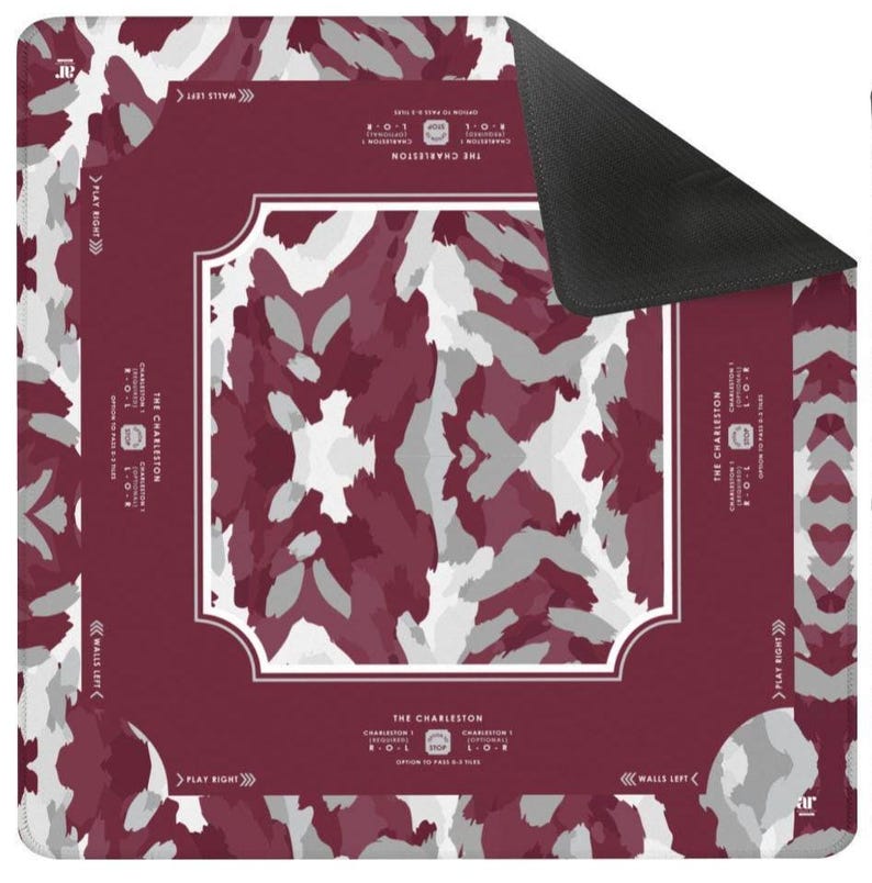 May include: A square game mat featuring a maroon, white, and gray abstract camouflage pattern. The center has a white-bordered frame, and the edges include text reading THE CHARLESTON, CHARLESTON 1, PLAY RIGHT, and WALLS LEFT with directional arrows.