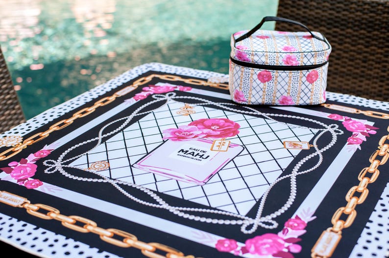 Op de afbeelding: Een decoratieve picknickdeken en bijpassende cosmetische tas. De deken heeft een zwart-wit ontwerp met gouden kettingaccenten, roze rozen en een parfumflesje. De cosmetische tas heeft een vergelijkbaar bloemenpatroon.