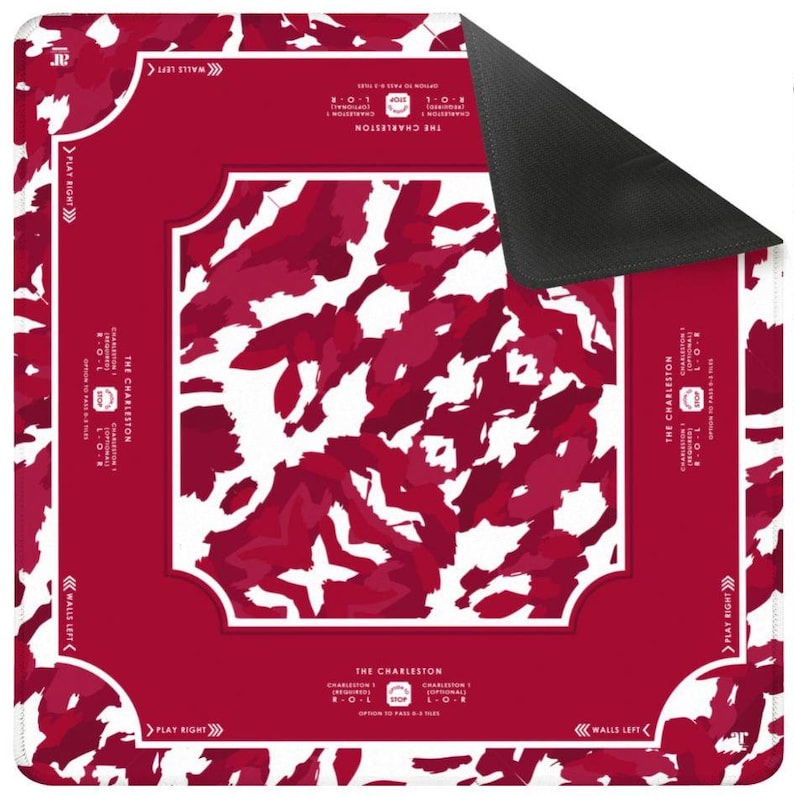 May include: A square game mat featuring a deep red and white camouflage-style pattern. The border includes text reading THE CHARLESTON, CHARLESTON 1, R-O-L, and directional arrows for PLAY RIGHT and WALLS LEFT. The underside of the mat is solid black.
