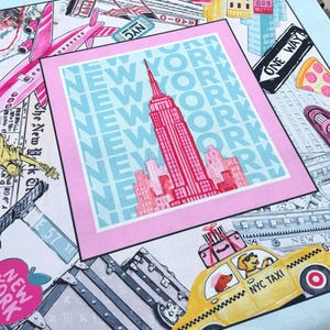 May include: A square scarf with a New York City theme. The design includes the Empire State Building, a yellow taxi with dogs, pink airplanes, and the words "New York" in a repeating pattern. The scarf has a light blue border.
