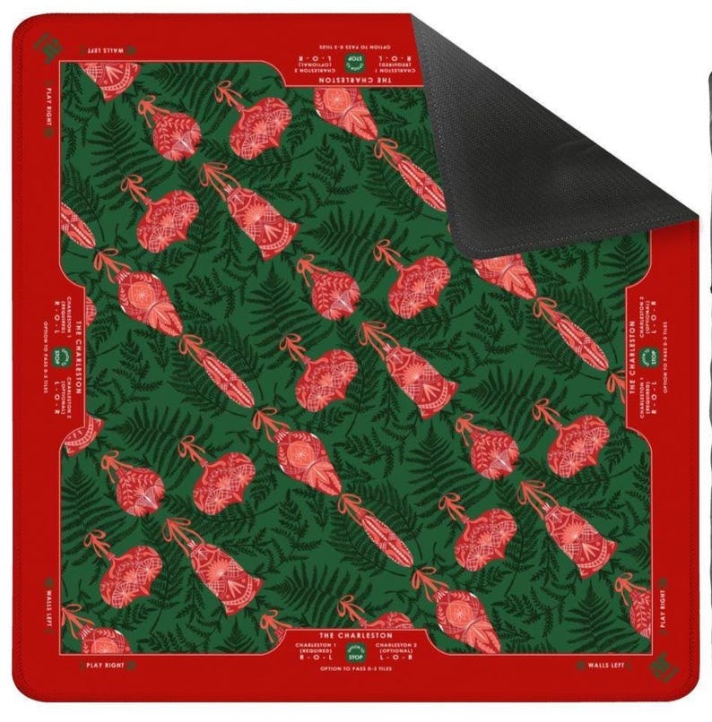 Pode incluir: Um tapete quadrado com um padr&atilde;o verde e vermelho com um design repetido de objetos vermelhos e folhas de samambaia. O tapete tem uma borda vermelha com o texto "THE CHARLESTON" e "PLAY RIGHT".