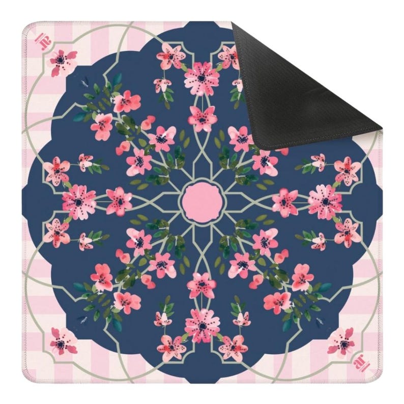 May include: A square floral patterned mat featuring a navy blue center with pink flowers and green leaves arranged in a circular design. The mat has a pink and white checkered border and a black corner.