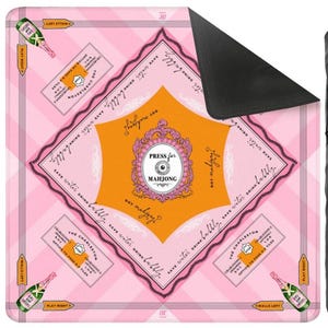 May include: Pink and orange Mahjong game mat with text that reads "Press for Mahjong" and "Save water drink bubbly." The mat features champagne bottles and game instructions. The mat has a black backing.