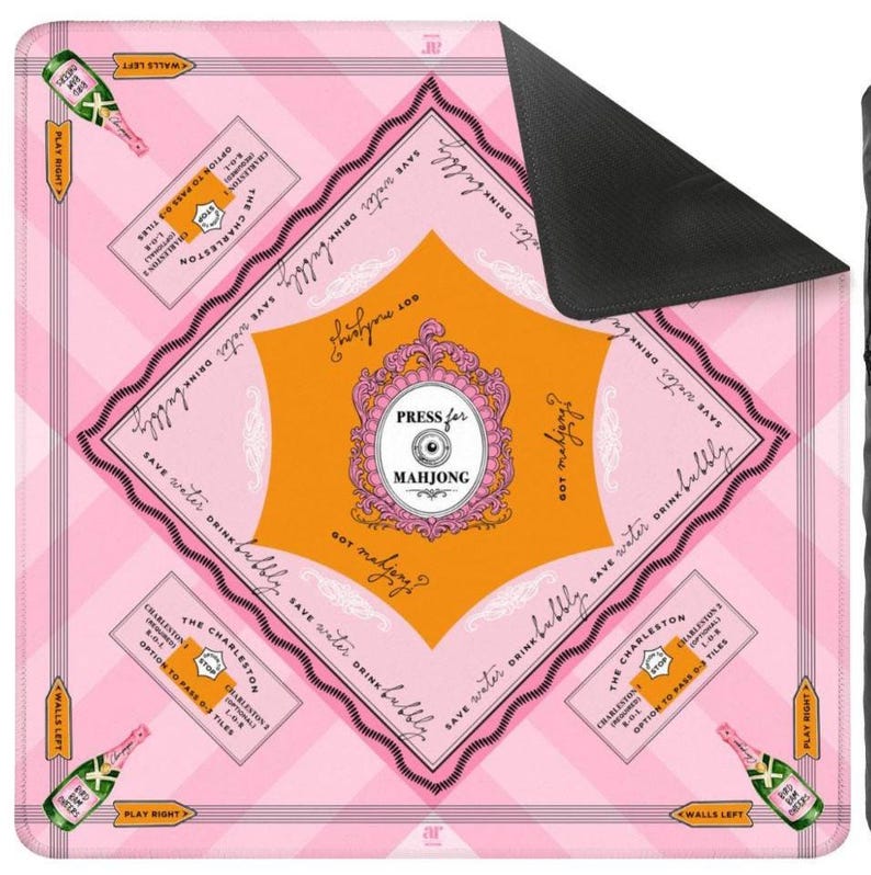 May include: Pink and orange Mahjong game mat with text that reads "Press for Mahjong" and "Save water drink bubbly." The mat features champagne bottles and game instructions. The mat has a black backing.