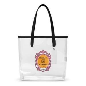 Puede incluir: Bolso tote transparente con asas y ribetes negros. El bolso presenta un emblema rosa y dorado que dice "Press for Mahjong". El diseño es transparente, permitiendo ver el contenido.