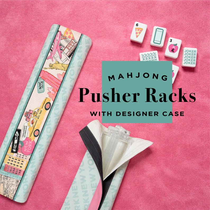 May include: Mahjong pusher racks with a designer case, featuring a New York City theme. The racks are light blue with a colorful design, and the case is open, revealing the clear plastic pusher. Mahjong tiles are also visible.