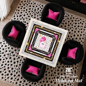 Op de afbeelding: Een vierkante witte Mahjong-mat met een parfumflesontwerp, omgeven door zwarte, gouden en roze accenten. De mat ligt op een zwart-wit patroonkleed, met vier zwarte fauteuils en roze kussens.
