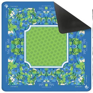 K&ouml;nnte beinhalten: Rechteckige Spielmatte mit blauem und gr&uuml;nem Blumenmuster und einem wei&szlig; umrandeten gr&uuml;nen Mittelteil. Die Matte hat einen blauen Rand mit dem Text "THE CHARLESTON", "WALLS LEFT" und "PLAY RIGHT".