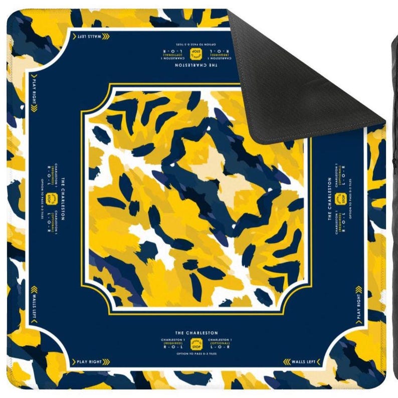 May include: A square mahjong mat featuring a central abstract pattern in yellow, navy blue, and white. The dark blue border includes white text reading THE CHARLESTON, directional arrows for PLAY RIGHT and WALLS LEFT, and game instructions.
