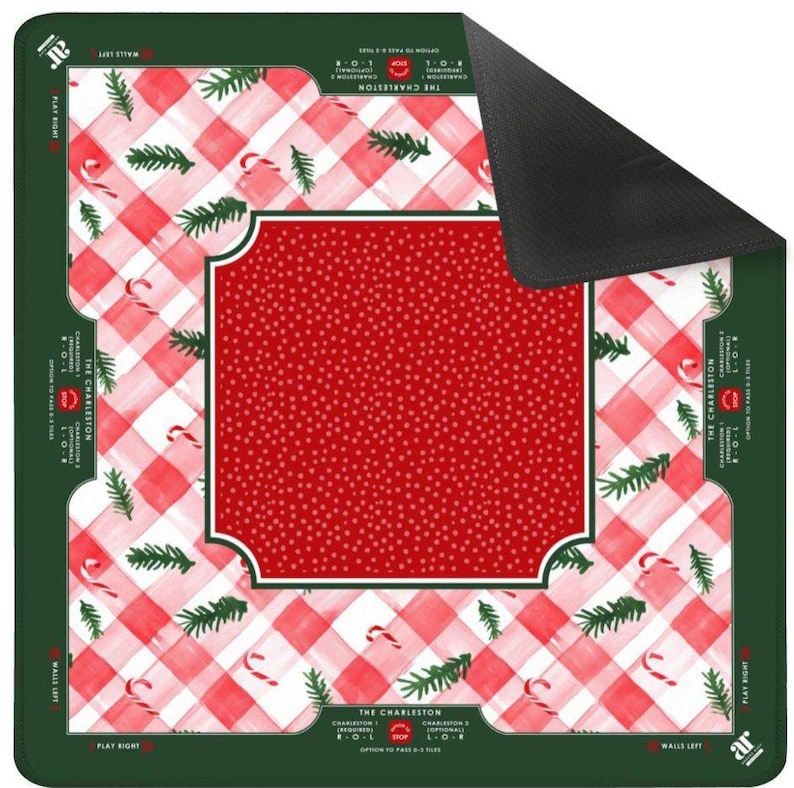 Op de afbeelding: Een vierkante kerstmat met een rood-wit geblokt patroon, zuurstokken en groene dennentakken. Het midden heeft een rood stippenontwerp binnen een wit omrand kader. De randen zijn groen met tekst.