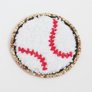 May include: A baseball-themed patch with a white, textured surface and red stitching. The patch has a gold glitter border and is round in shape. This patch is suitable for sports fans.