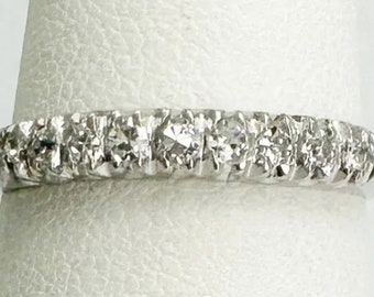 Op de afbeelding: Een zilveren bandring met een rij kleine, heldere diamanten in pavé-zetting.
