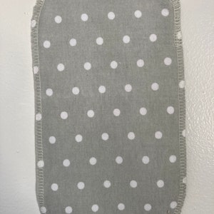 May include: A gray fabric square with white polka dots, the edges are sewn with a white thread.