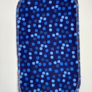 May include: A blue fabric rectangle with a white stitched border. The fabric has a pattern of blue and light blue polka dots.