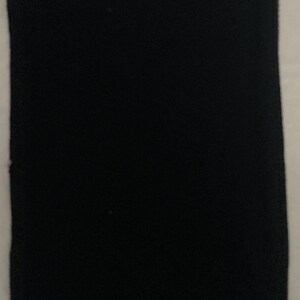 Puede incluir: Un parche de tela negro con forma rectangular ligeramente redondeada.