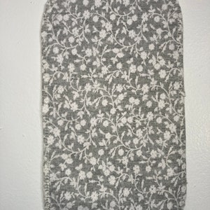 May include: A gray fabric square with a white floral pattern. The fabric is sewn around the edges.