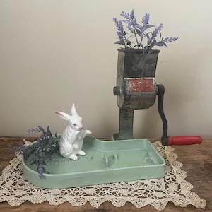 May include: A vintage green ceramic tray with a white porcelain rabbit figurine and a metal food grinder with a red handle. The tray is decorated with lavender sprigs.