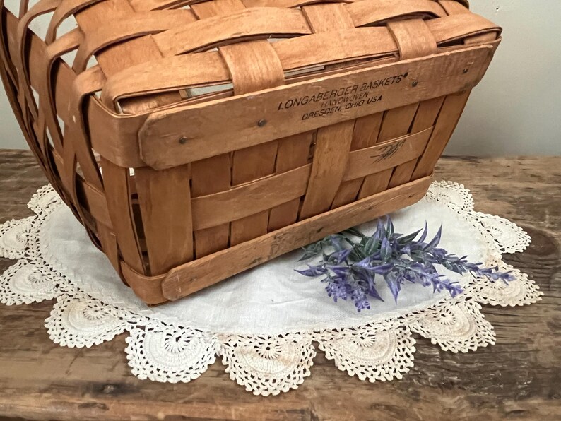May include: A vintage wooden basket with a woven design. The basket has a label that reads "Longaberger Baskets,  Hawthorn, Dresden, Ohio USA".