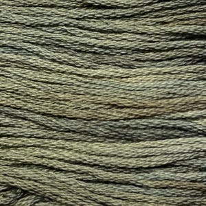 May include: Close-up of a skein of green embroidery floss. The floss is a variegated color, with shades of light and dark green.