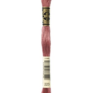 May include: A spool of DMC embroidery floss in color 223, a muted rose pink. The spool is labeled with the DMC logo and the number 223.