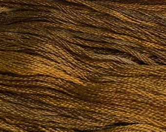 May include: Close-up of a bundle of brown and gold yarn. The yarn appears to be made of a natural fiber, with variations in color creating a textured appearance. Ideal for knitting, crochet, or other fiber arts projects.