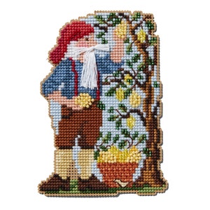 May include: A cross-stitch pattern of a gnome standing next to a lemon tree with a basket of lemons at the base. The gnome is wearing a red hat, blue shirt, brown pants, and white boots. The tree has green leaves and yellow lemons.