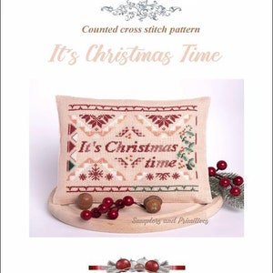May include: A counted cross stitch pattern sampler with a beige background and red, green, and white embroidery. The sampler features the text "It's Christmas Time" in red lettering.