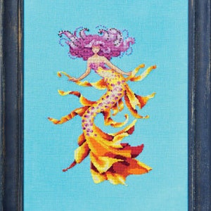 May include: A cross-stitch embroidery of a mermaid with pink hair and a yellow tail. The mermaid is surrounded by a blue background.