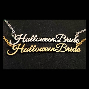 May include: Two necklaces with the words "Halloween Bride" in a cursive font. The top necklace is silver and the bottom necklace is gold.