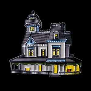 May include: A white and grey enamel pin depicting a haunted house with a tower, windows, and a porch. The house has a green roof and a yellow glow coming from the windows. There is a jack-o-lantern on the porch.