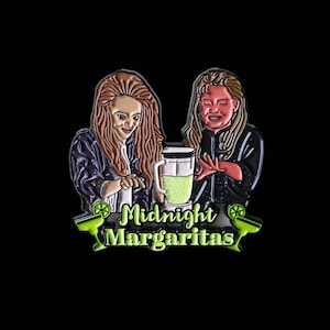 May include: Enamel pin depicting two women with long hair, standing near a blender with a green liquid. The pin reads "Midnight Margaritas" in green and white, with lime and margarita glass accents. The women are wearing dark jackets.