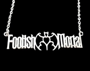 Puede incluir: Collar de plata con un colgante que dice "Foolish Mortal" con un murciélago y un corazón en el medio.