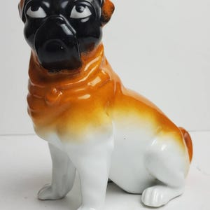 Peut inclure: Figurine de bouledogue en céramique, assis. Le chien a un visage et des oreilles noirs, avec un corps beige et blanc. La figurine est brillante et détaillée. Un objet décoratif pour les amateurs de chiens.