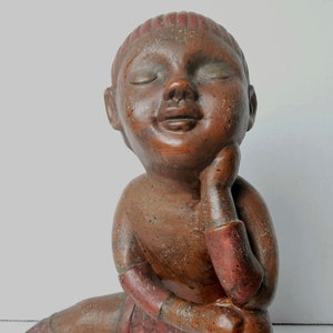 Peut inclure: Une sculpture en terre cuite d'une personne assise, le menton reposant sur la main. La sculpture est peinte dans des tons de brun et de rouge.
