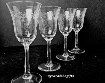 May include: Set of four clear glass stemmed wine glasses with a floral etched design.