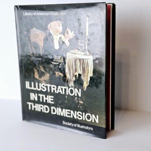 May include: A hardcover book titled "Illustration in the Third Dimension" by the Society of Illustrators. The cover features a dark, moody illustration of a person at a table with a candle and wine glass. The book is from the Library of American Illustration.
