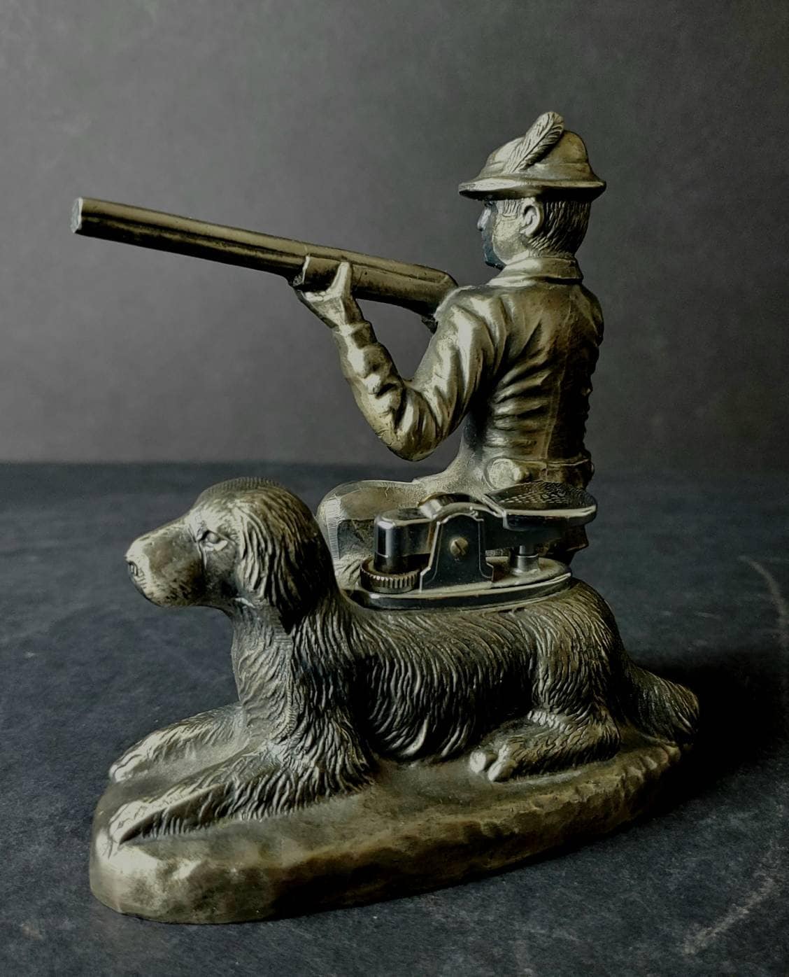 ライフルと犬のテーブルライターを持ったひざまずくハンターの置物